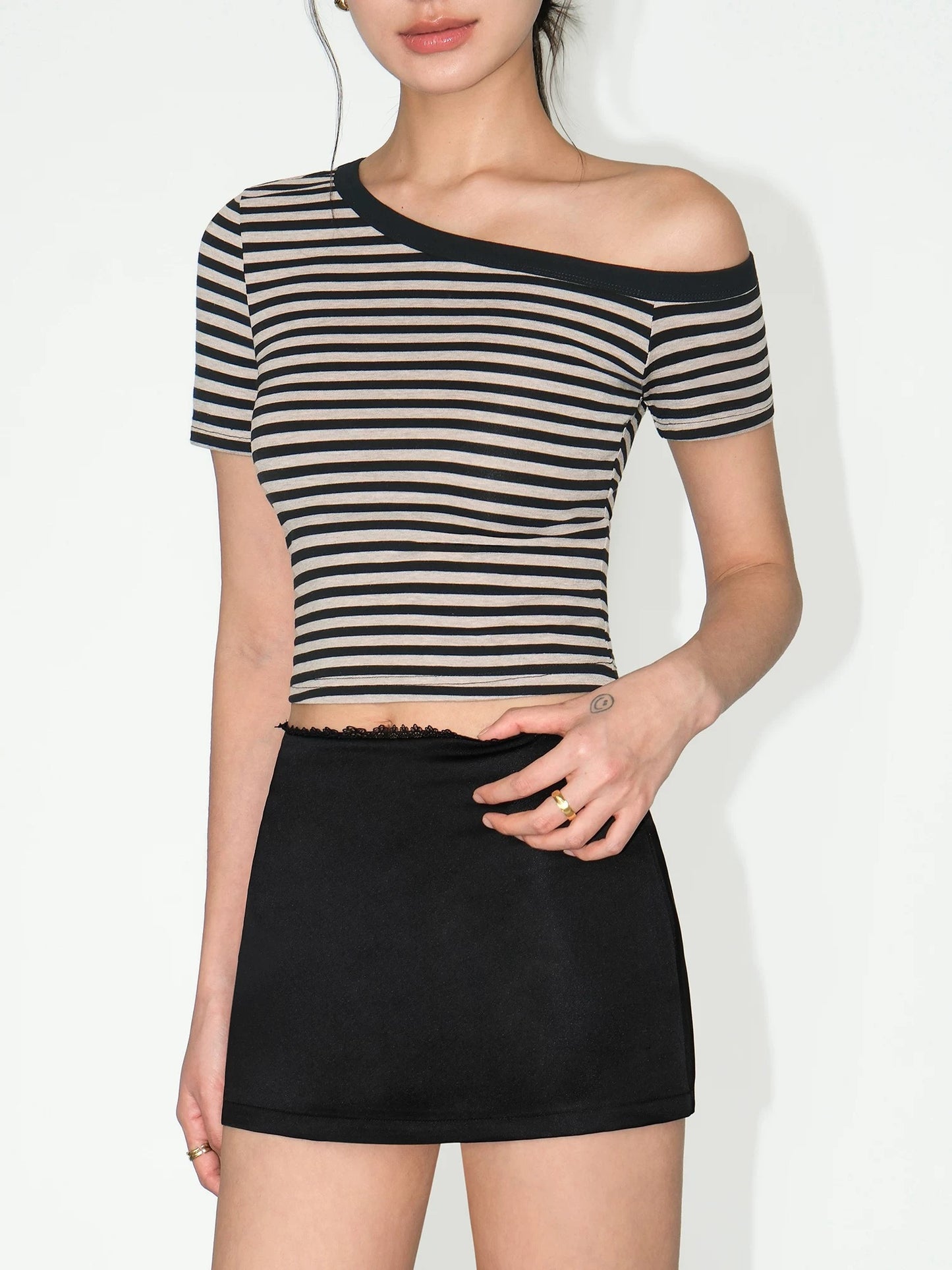 Person wearing a black and beige striped top and black skirt on a white background