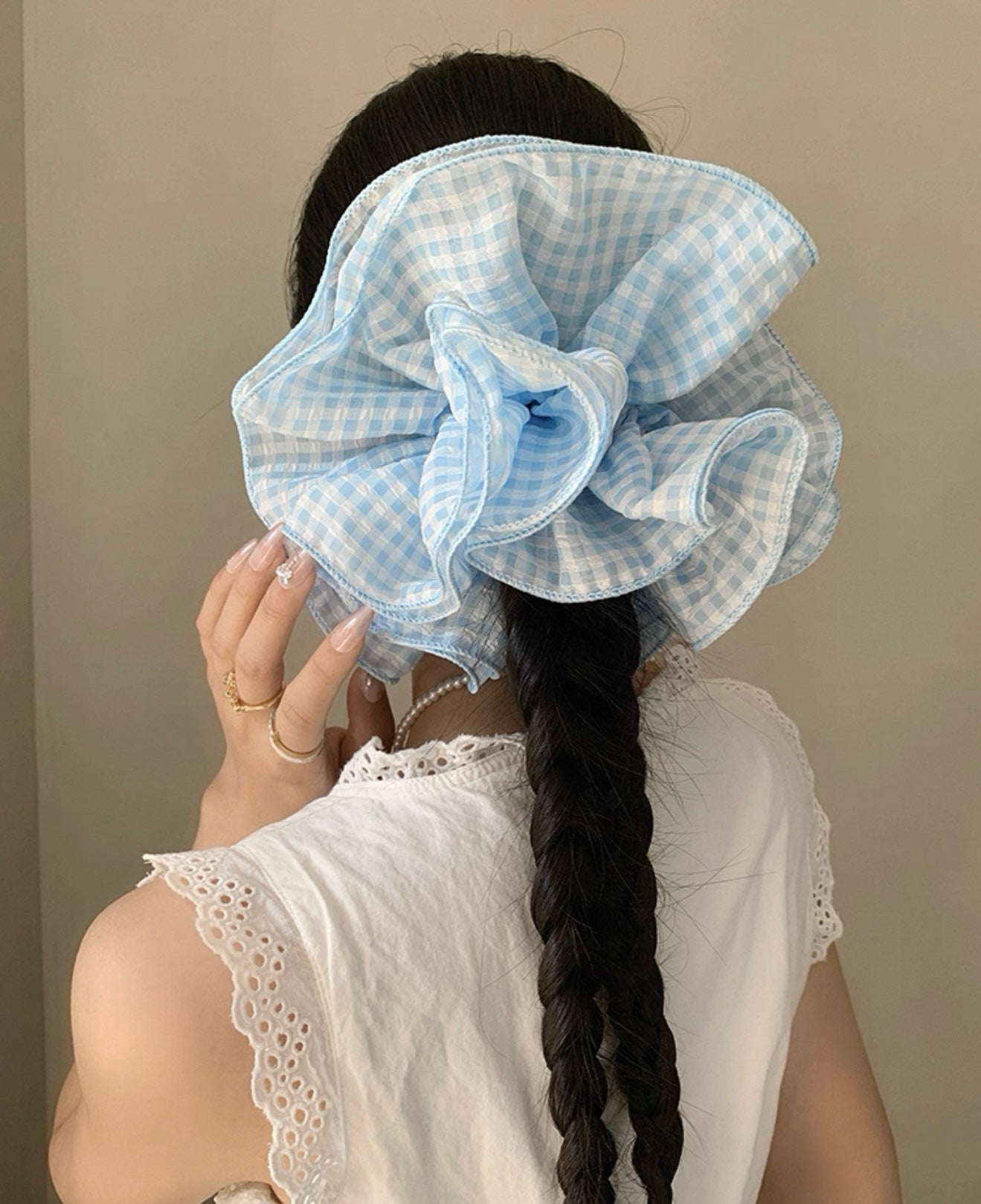 Person wearing a large blue checkered headscarf with a plain background