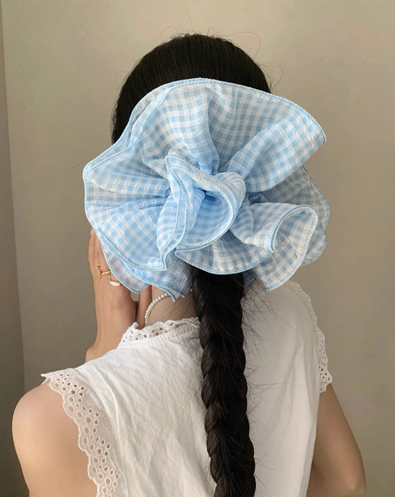 Person wearing a large blue checkered scrunchie with a plain background