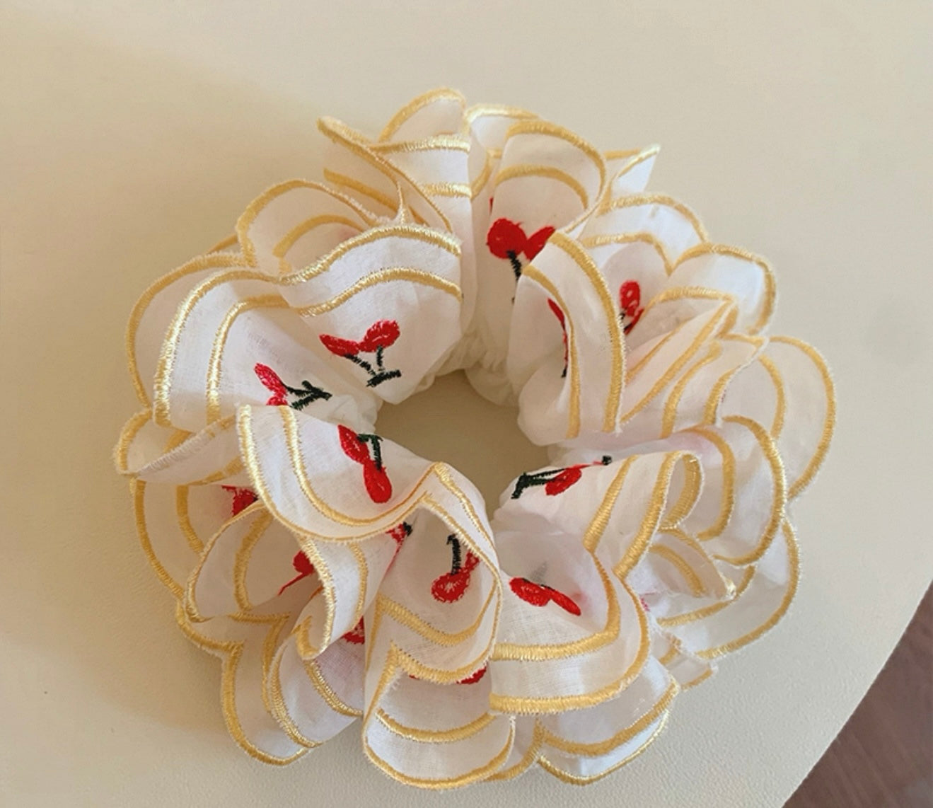 White scrunchie with red and black floral designs on a beige background