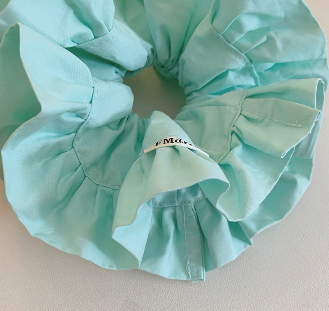 Light blue satin hair scrunchie on a light background