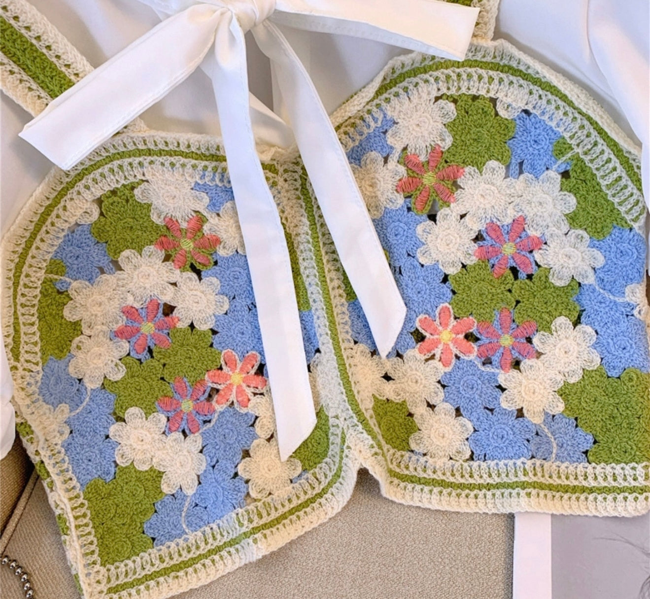 Pair of crocheted oven mitts with floral pattern on a white background