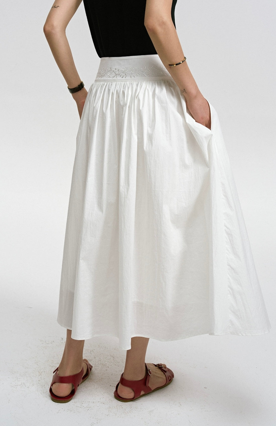 Person wearing a white skirt and black top on a white background