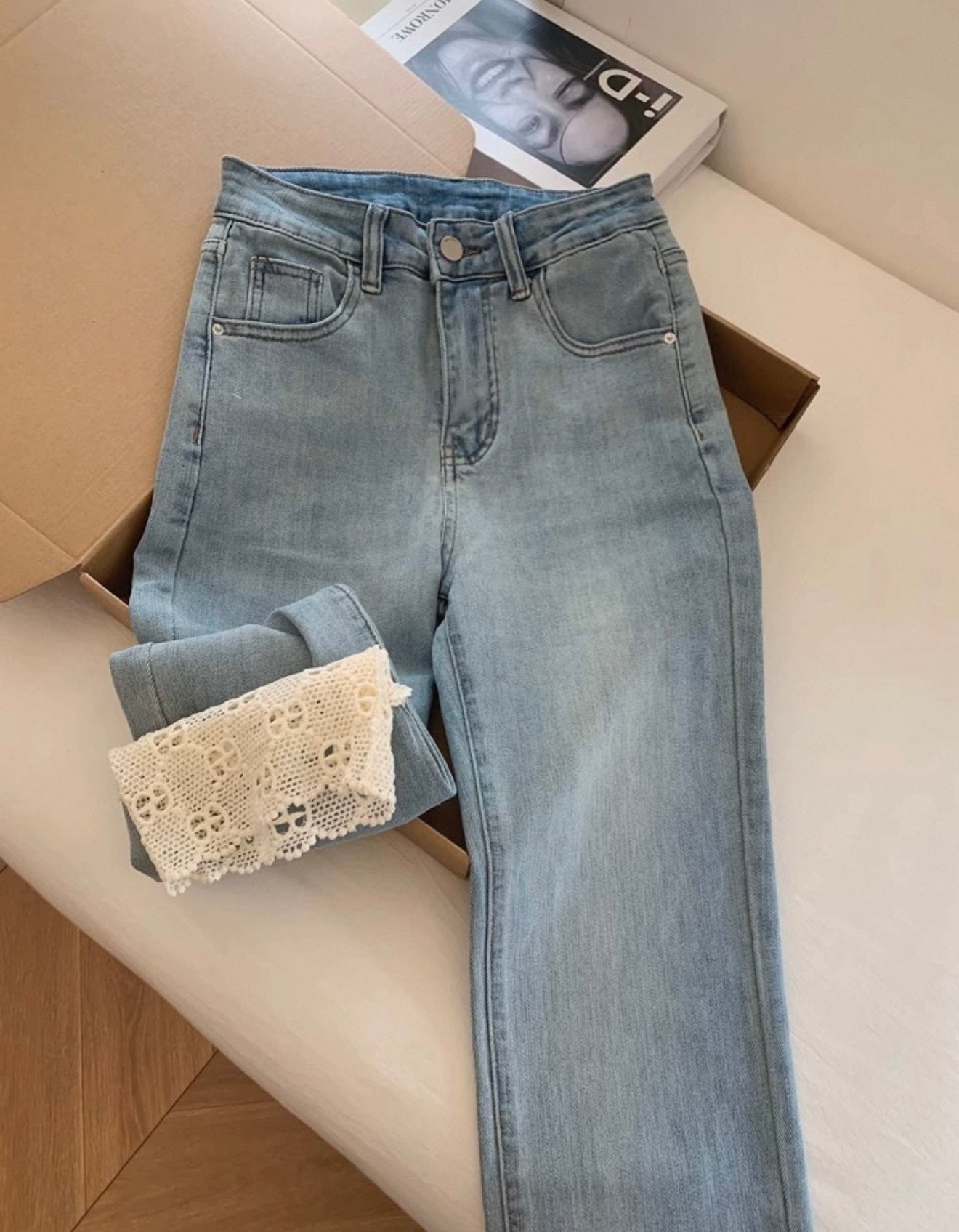 Light blue jeans with lace cuffs on a white surface