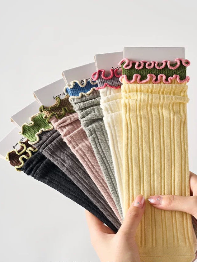Set of colorful ribbed socks held by a hand on a light gray background