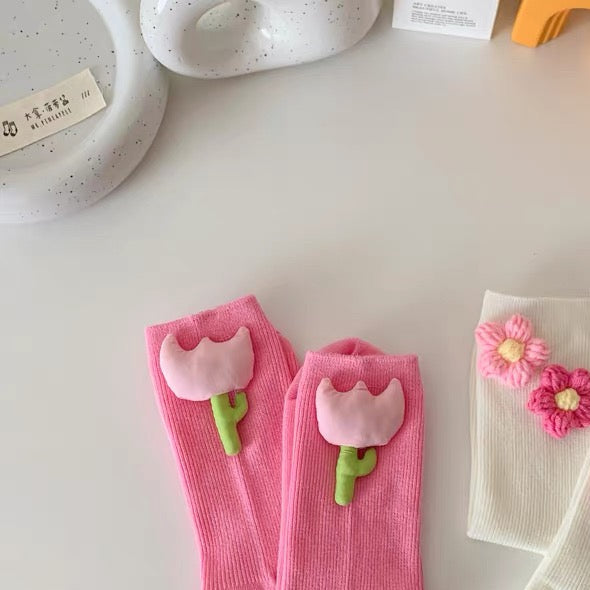 Pink socks with flower designs on a white surface