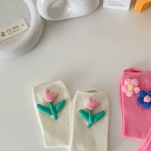 Two pairs of socks with floral designs on a light gray surface.