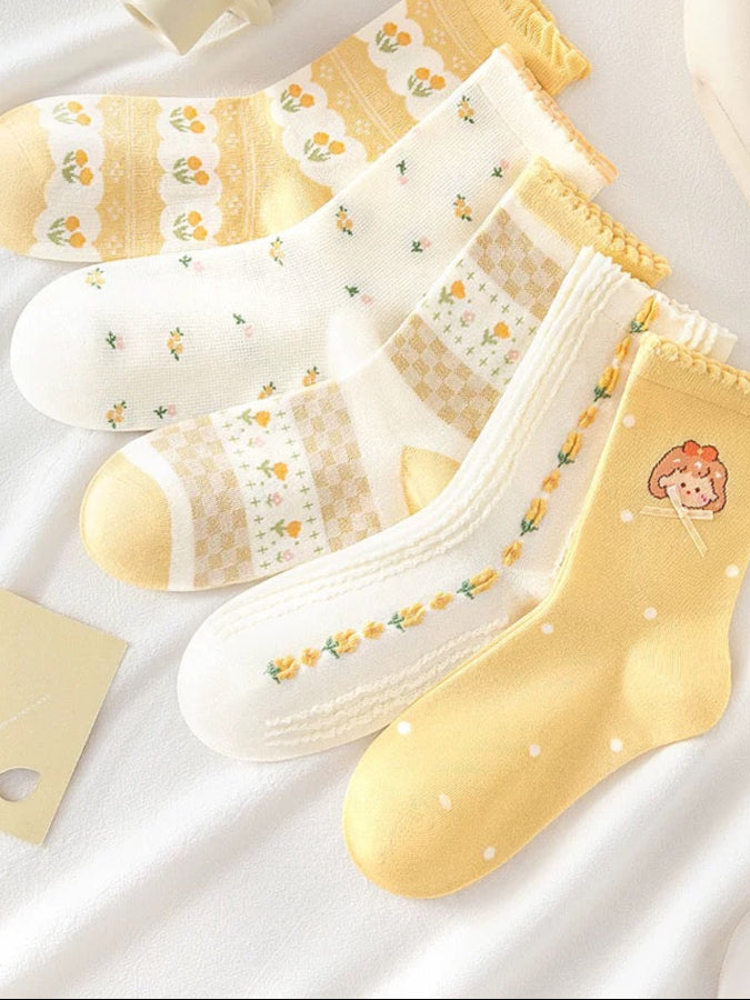 Set of yellow and white socks with floral patterns on a light background