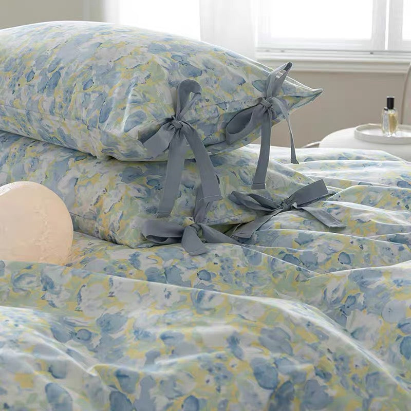 Floral bedding set with tied gray ribbons on a bed.