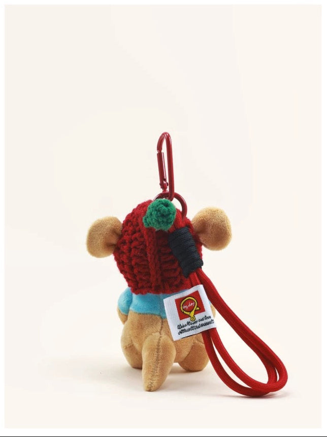 Small plush toy with a red hat and green pom-pom, attached to a keychain, on a white background with '' branding.