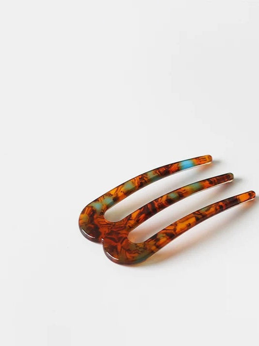 Tortoiseshell hair comb on a white background with '' branding.