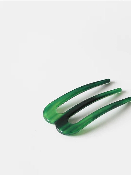 Green hair clip on a white background with '' branding.
