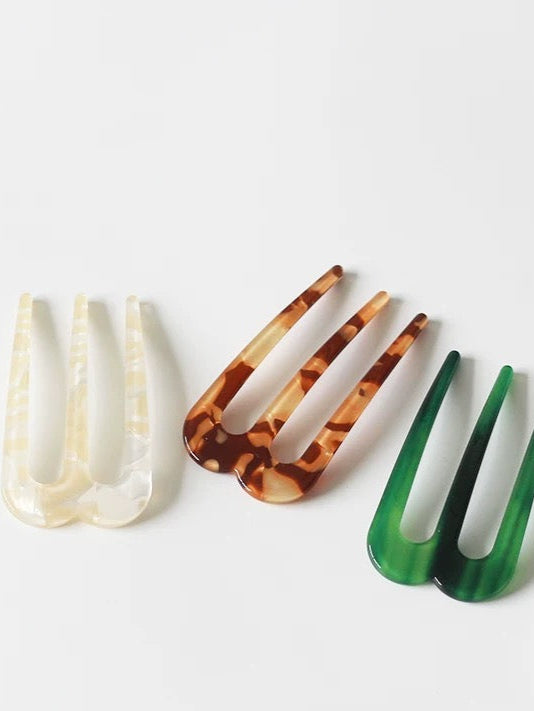 Three hair combs in different colors on a white background with ' branding.