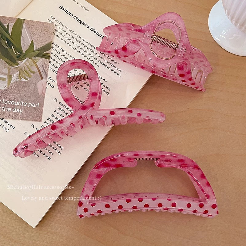 Pink hair clips with polka dot pattern on a wooden surface