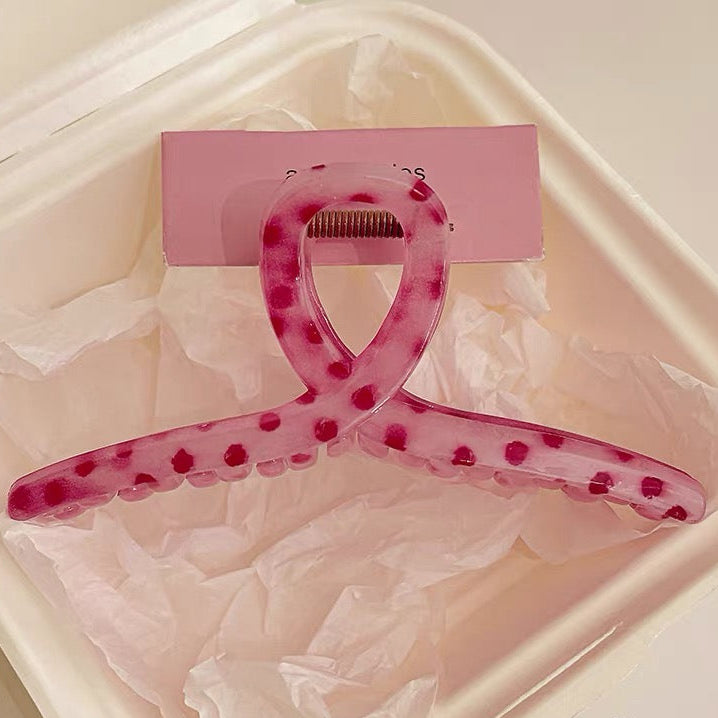 Pink hair clip with a clear design on a light pink background