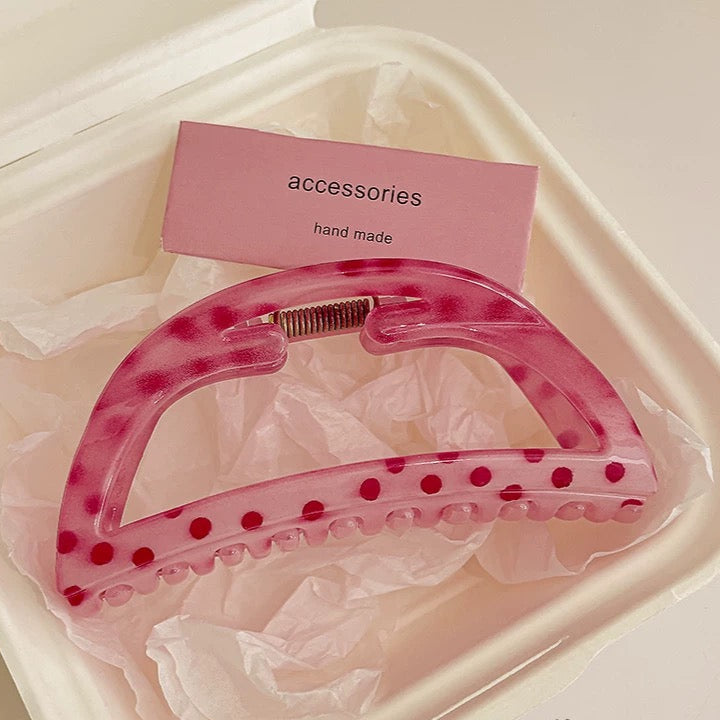 Pink hair clip with red polka dots on a white tray with a pink card labeled 'accessories hand made'.