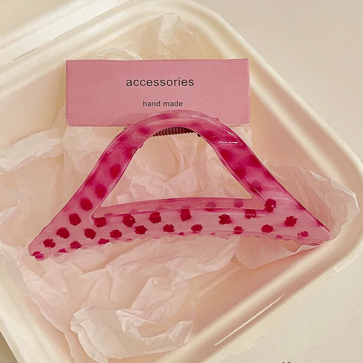 Pink hair accessory with a label indicating 'handmade' on a light pink background