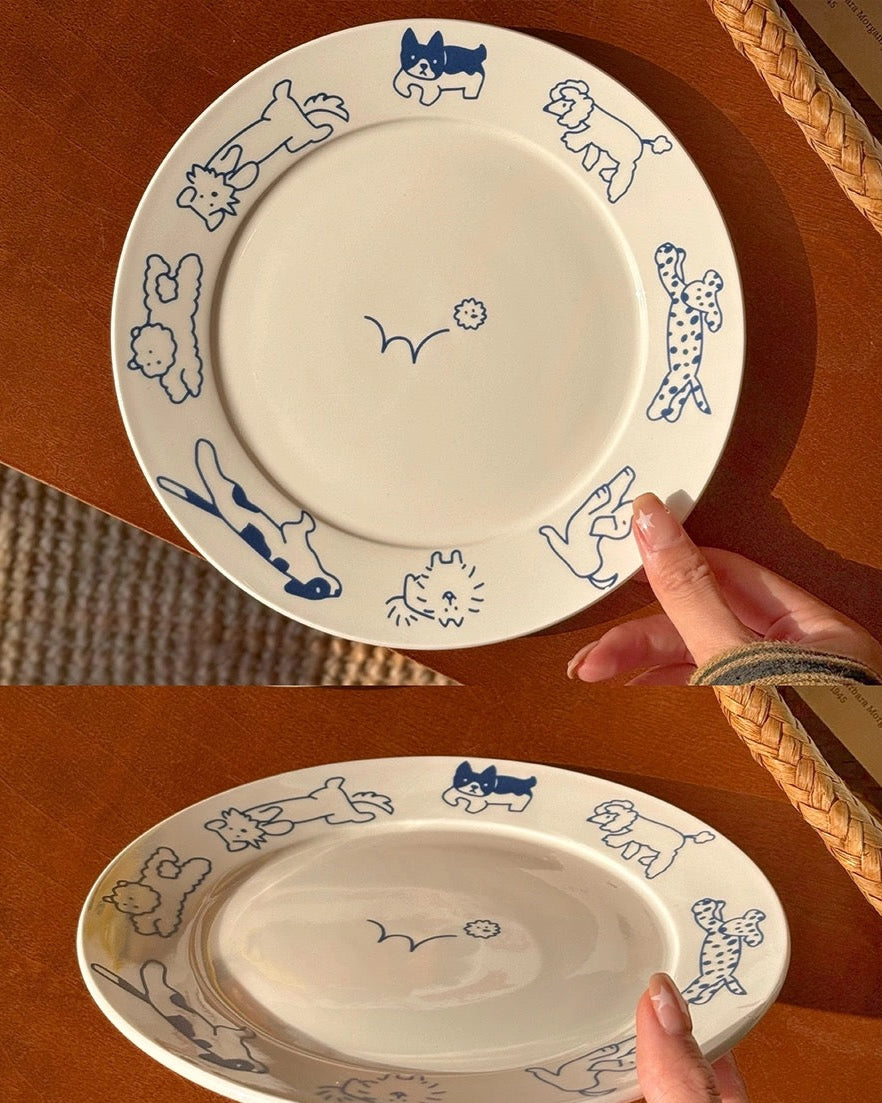 Two ceramic plates with animal illustrations on a wooden surface, one held by a hand.