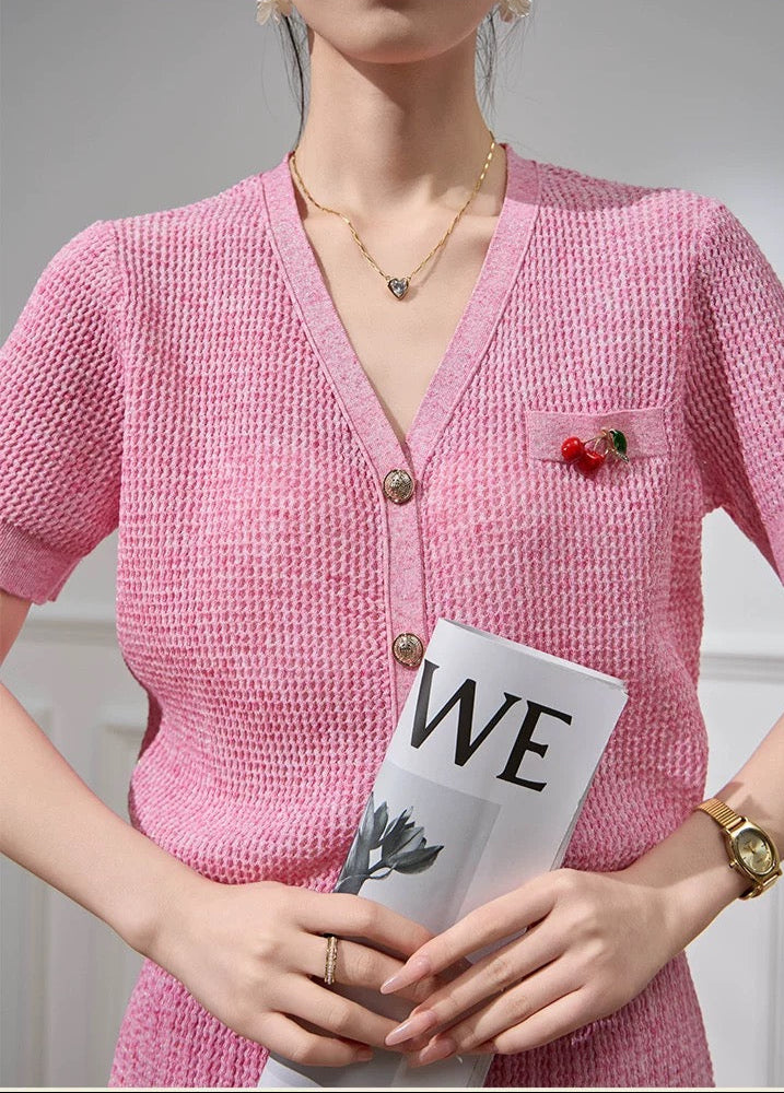 Person wearing a pink knitted cardigan holding a magazine with 'WE' on the cover.