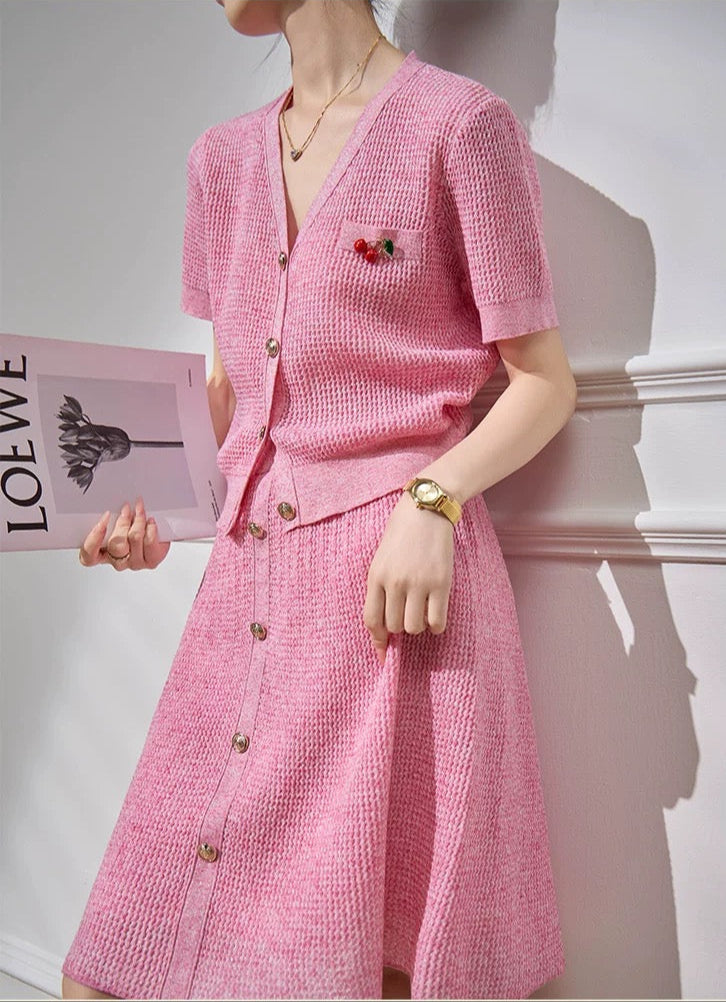 Person wearing a pink dress holding a magazine with 'LOEWE' branding.