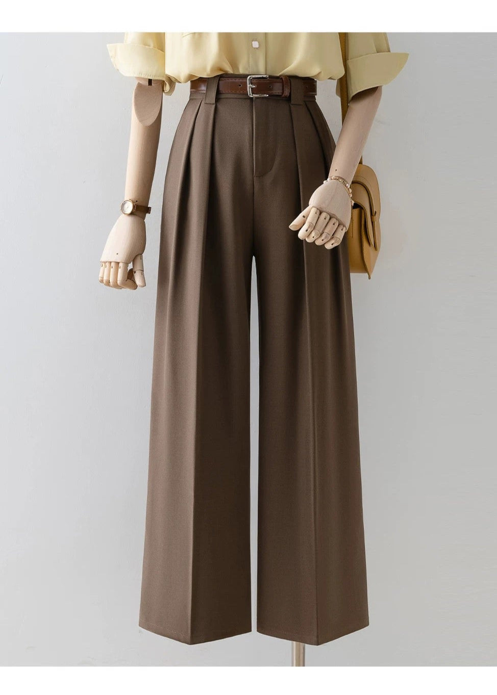 Mannequin wearing a yellow shirt and brown wide-leg pants with a belt on a gray background.