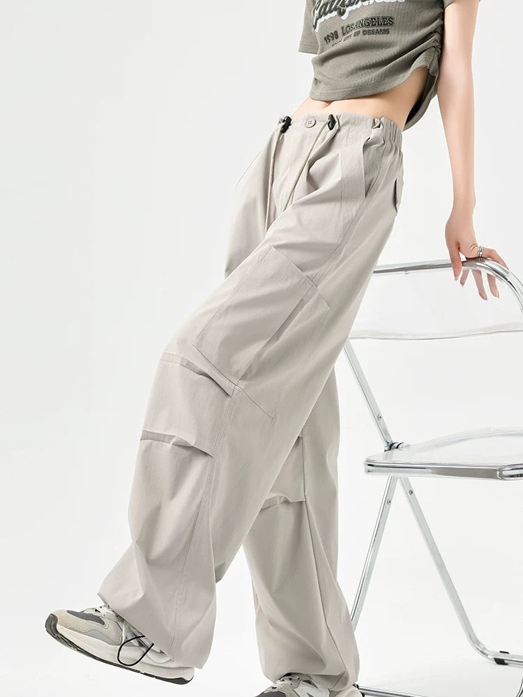 Person wearing light gray cargo pants and a graphic t-shirt on a white background