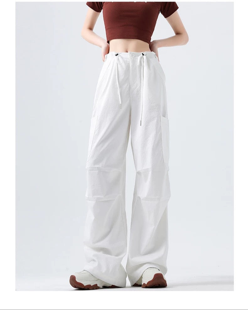 Person wearing a brown top and white wide-leg pants on a white background