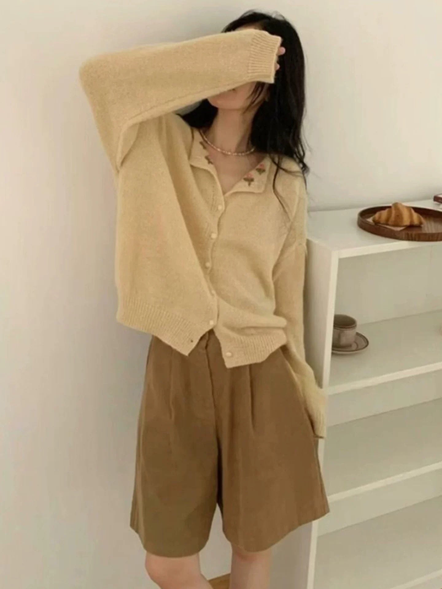 Person wearing a beige outfit with shorts in a minimal indoor setting
