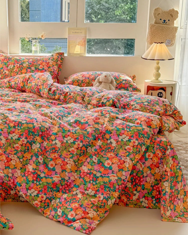 Colorful floral bedspread on a bed in a bright room with windows.