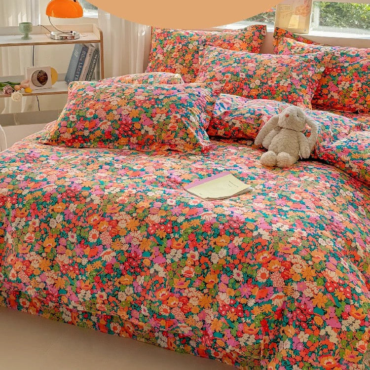 Colorful floral bedspread on a bed with pillows and a teddy bear, in a room setting.