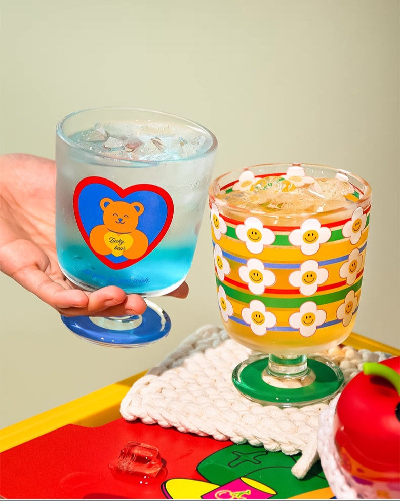 Two colorful glasses with a heart design on a textured surface.