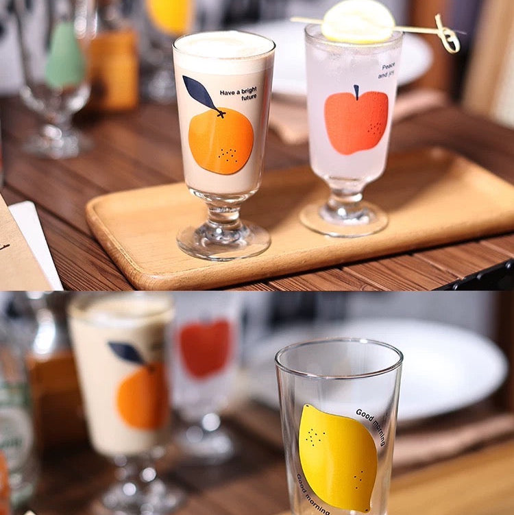 Two glasses with fruit designs on a wooden tray