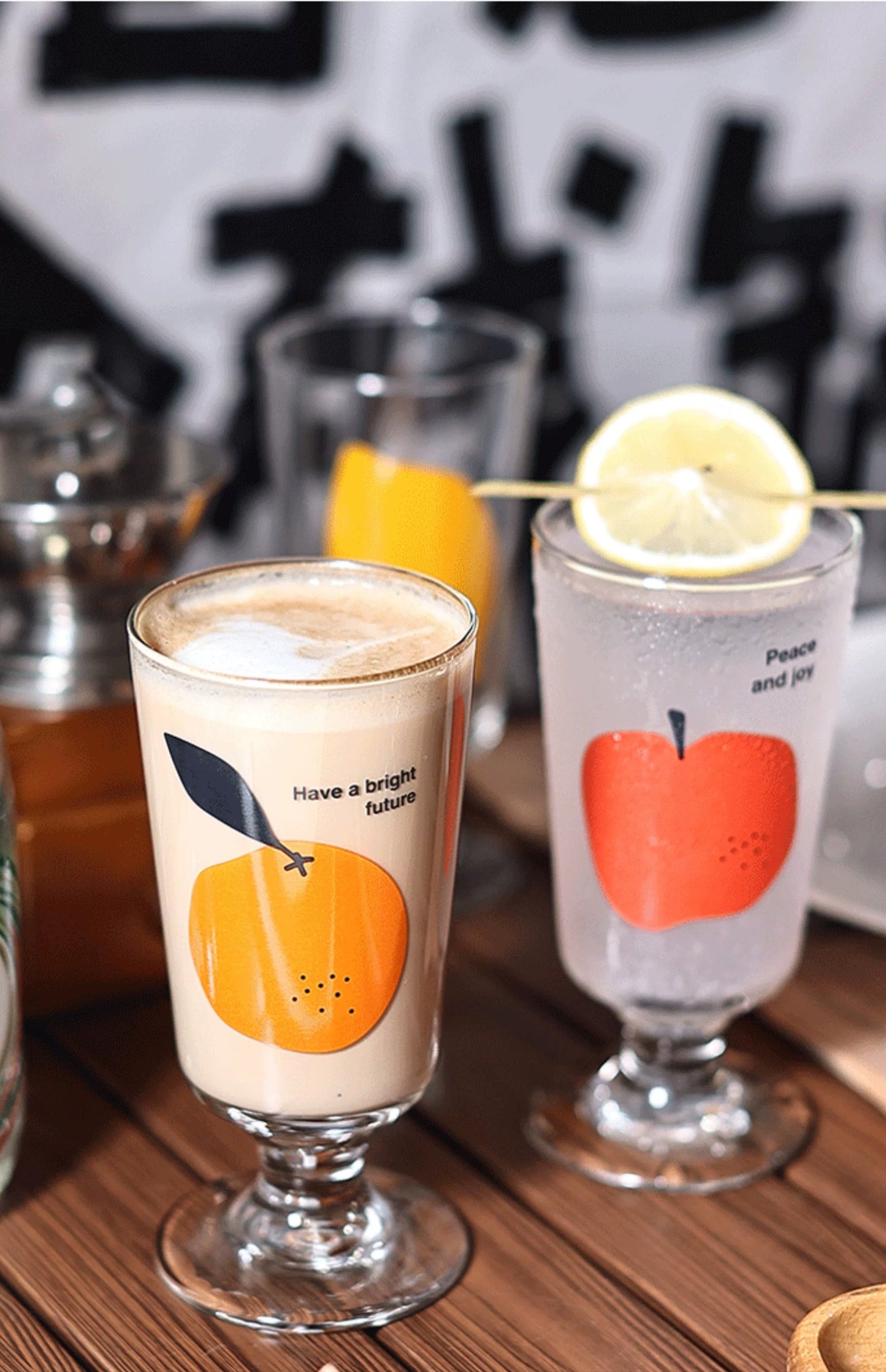 Two glasses with fruit-themed designs on a wooden surface.