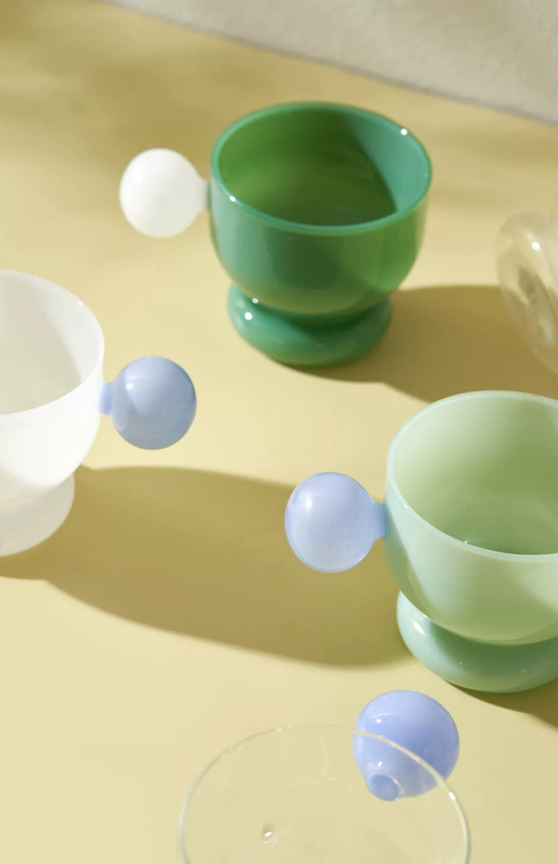Green egg cups with blue egg-shaped objects on a yellow surface