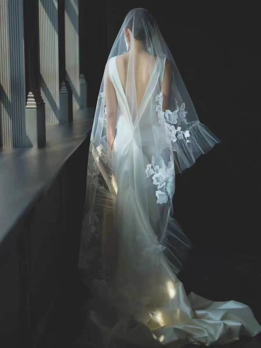 Woman in a wedding dress with a long veil in a dimly lit room