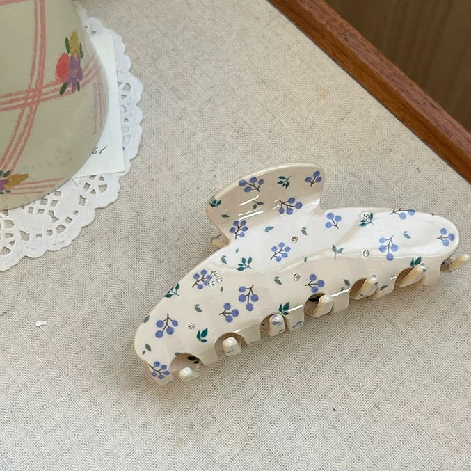Floral-patterned hair clip on a textured surface with text indicating size.