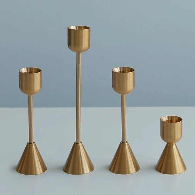 Set of four gold candle holders on a light gray background