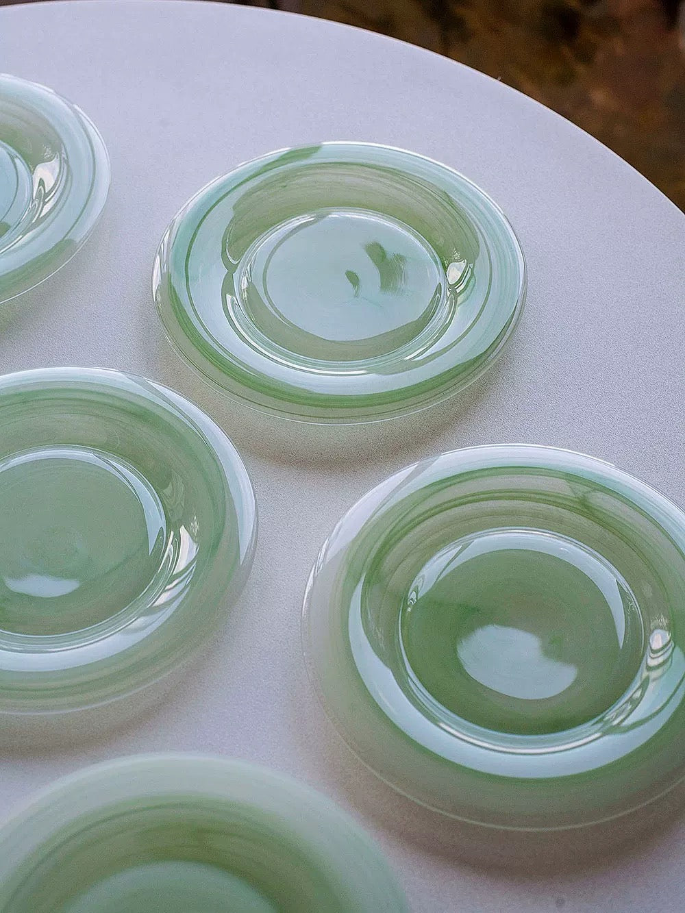 Set of green ceramic plates on a white surface
