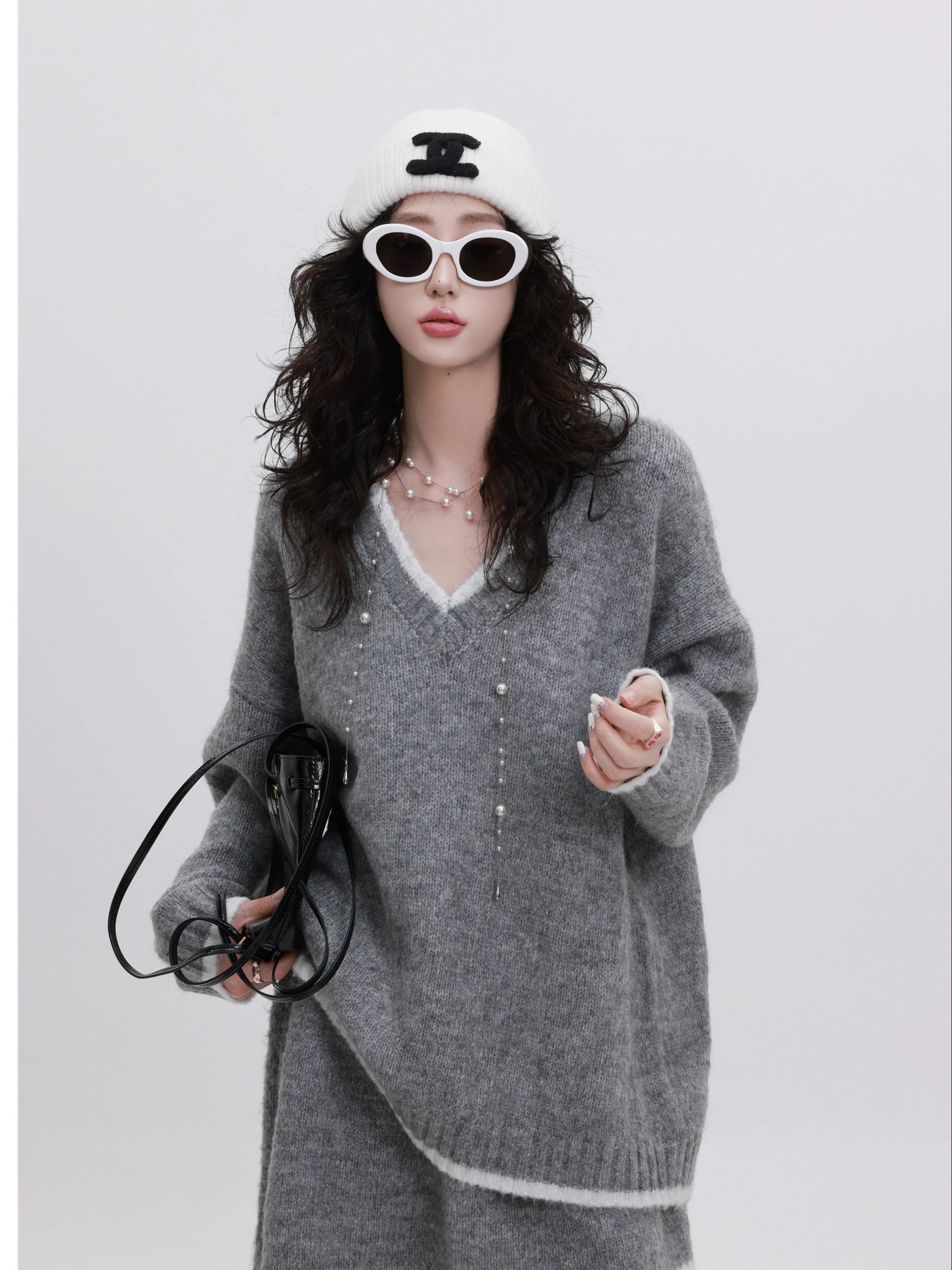 Woman wearing a gray sweater with sunglasses and a white cap on a white background, featuring 'YINGZI' collection text.