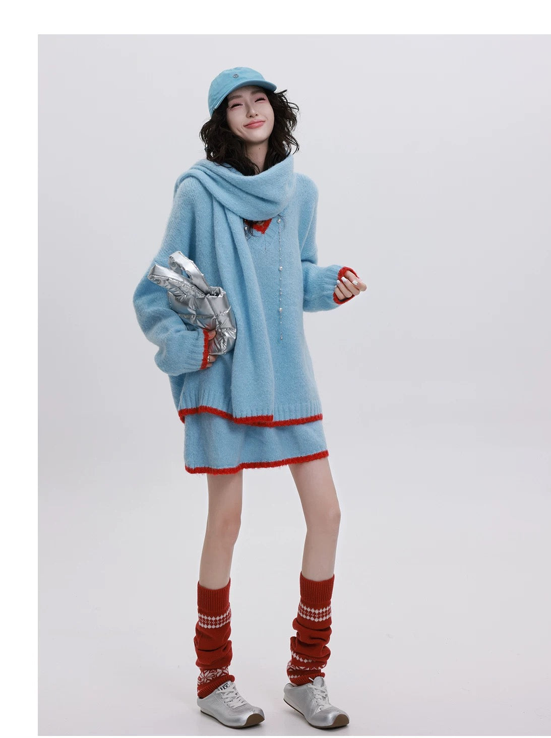 Person wearing a light blue dress with red trim, red socks, and a matching hat on a white background.