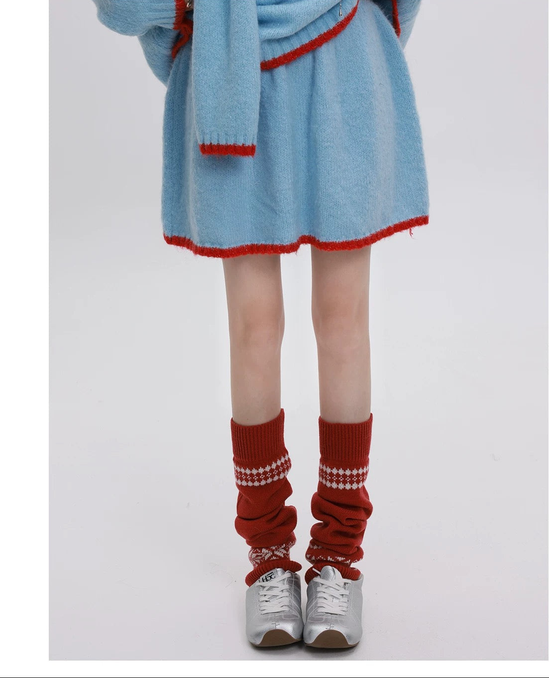 Person wearing a blue dress with red trim, red socks, and silver shoes on a white background.
