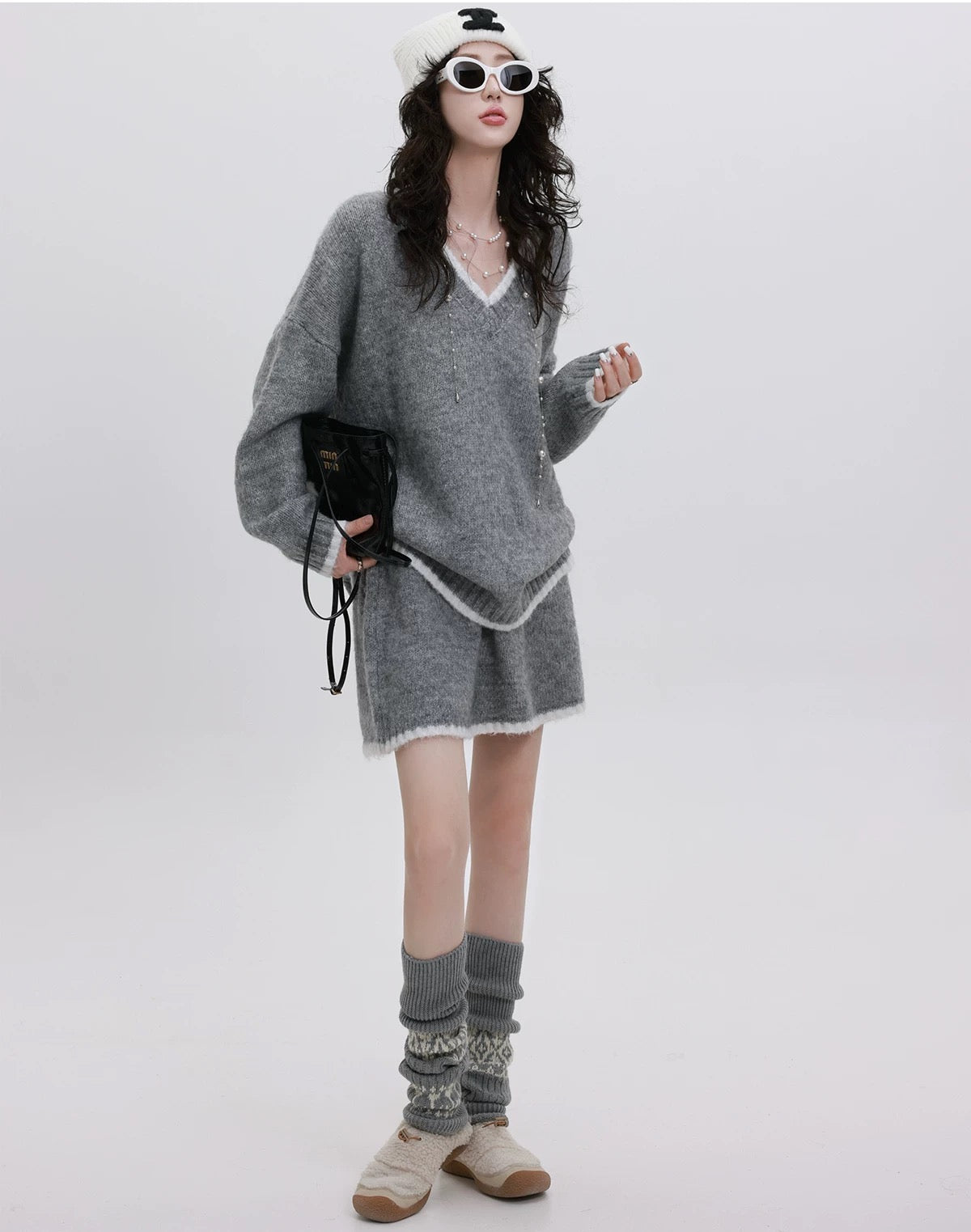 Person wearing a gray sweater dress with matching socks on a white background