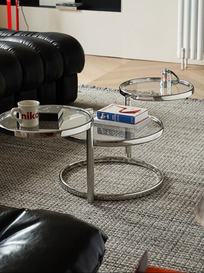 Modern living room with glass coffee table and black sofa, featuring the brand 'Less'.