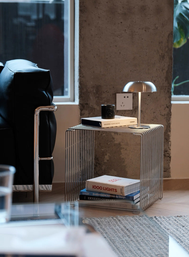 Modern living room with a black sofa, glass side table, and decorative items.
