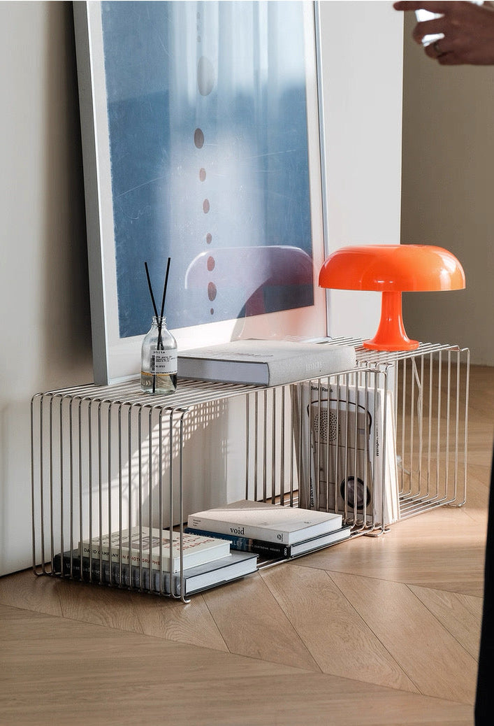 Modern office desk with a large screen monitor, orange lamp, and books in a minimalistic office setting.