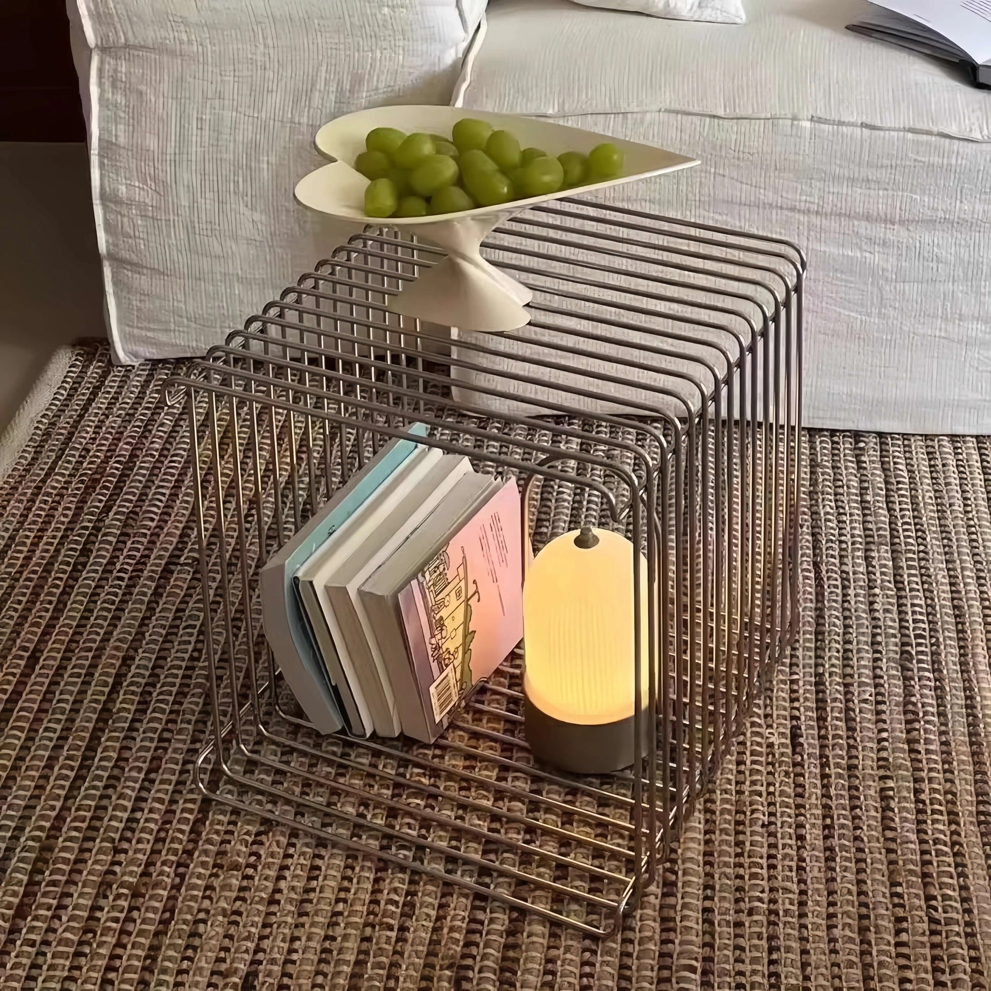 Wire side table with books and a lamp on a textured surface