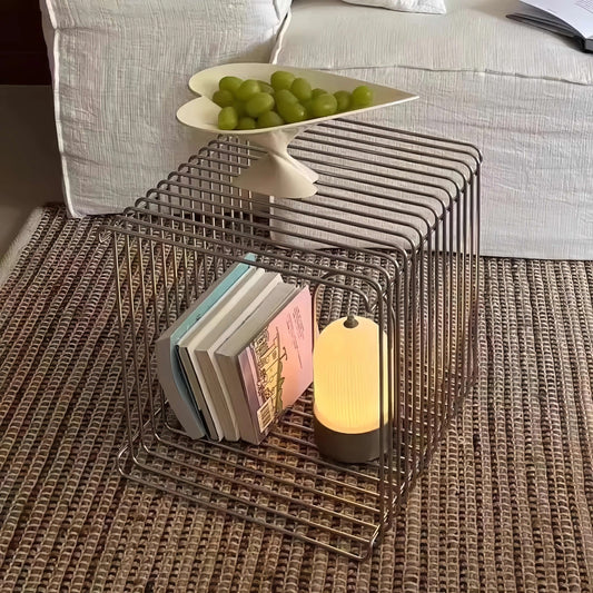 Wire side table with books and a lamp on a textured surface
