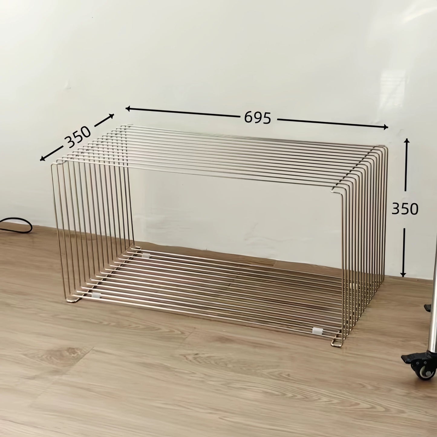 Metal wire basket with dimensions on a wooden floor against a white wall