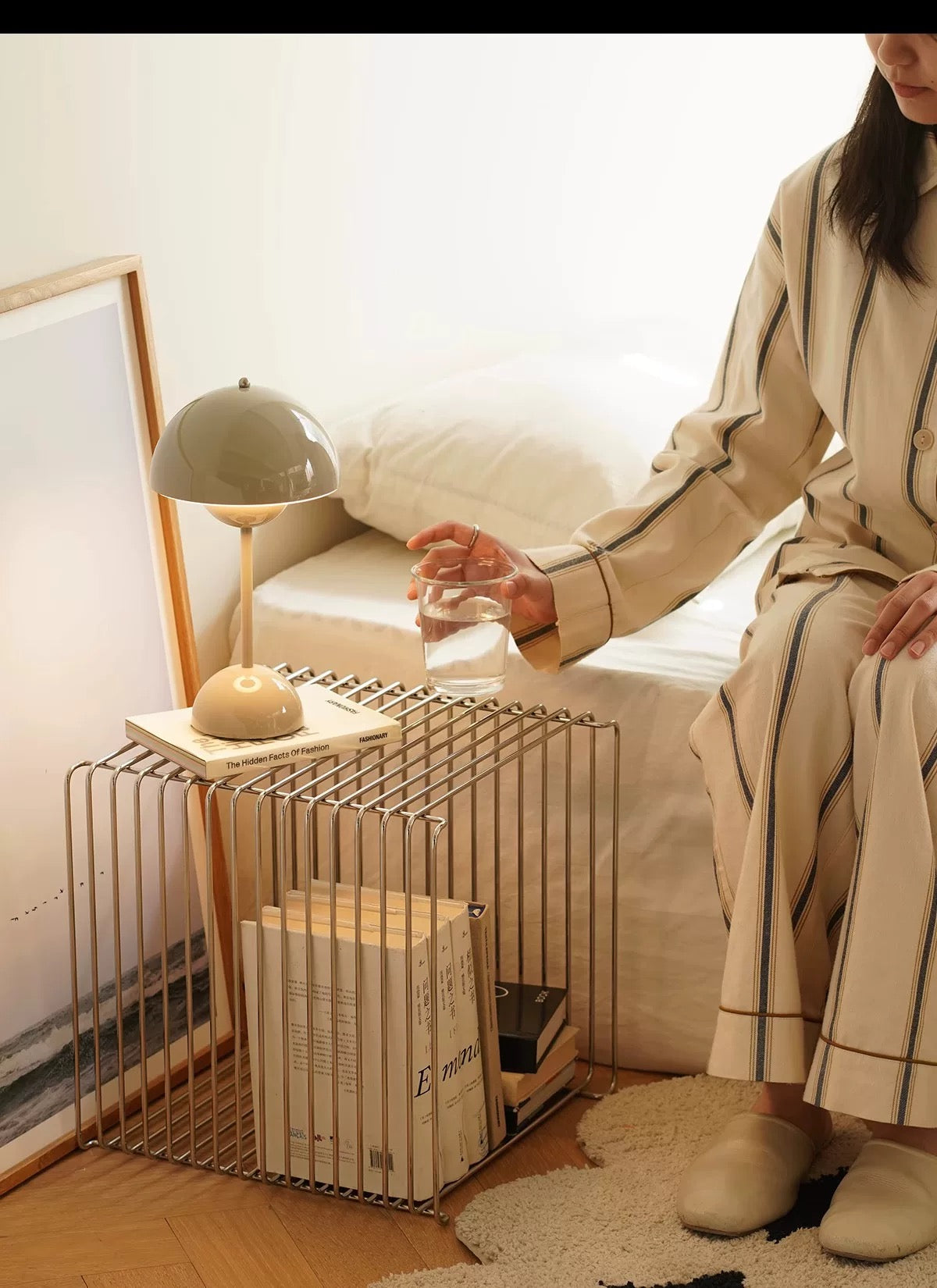 Person sitting on a couch with a side table and lamp in a cozy living room.