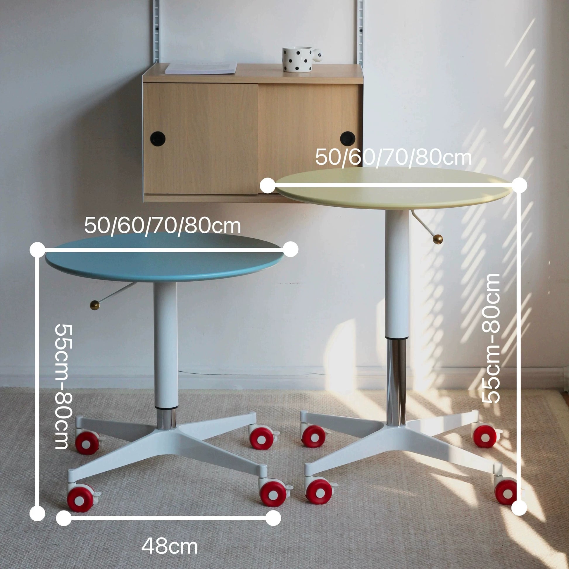Two adjustable height tables with measurement markings in a room setting.